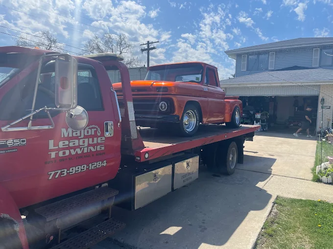 Classic orange pickup truck delivered on a flatbed to a Chicago driveway