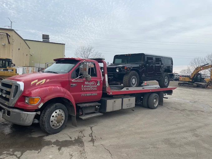 Large black SUV loaded on a flatbed in an equipment yard